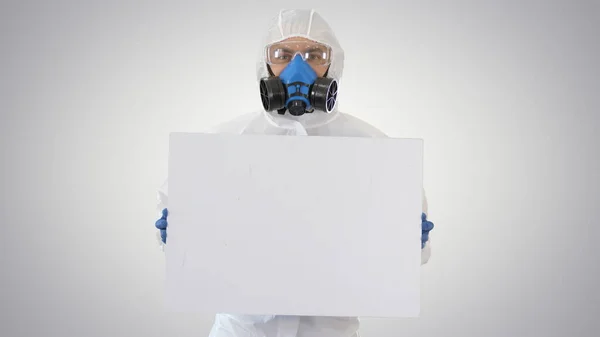 Lab scientist in safety suit holding empty white board on gradient background.
