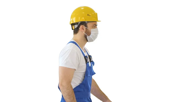 白い背景を歩く硬い帽子と仮面を被った建設労働者. — ストック写真