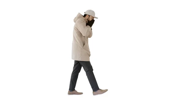 Homem caucasiano de chapéu e casaco tosse andando sobre fundo branco . — Fotografia de Stock