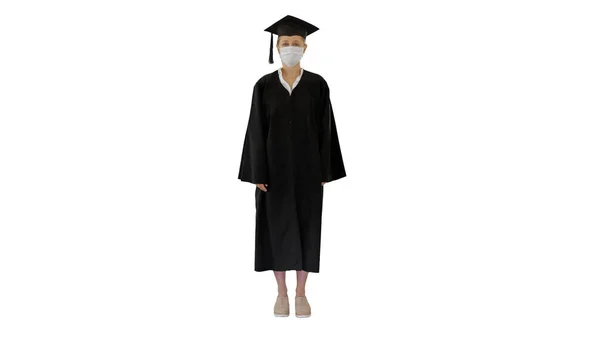 Vrouwelijke afgestudeerde student in een medisch masker staande op witte achtergrond. — Stockfoto