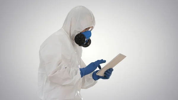 Cientista ou docrot vestindo trajes de risco biológico e máscaras protetoras usando tablet digital enquanto caminha em fundo gradiente . — Fotografia de Stock