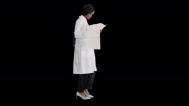 Alpha Channel 'da yürüyen ve kardiyogram kayıtlarına bakan Afro-Amerikalı doktor kadın.