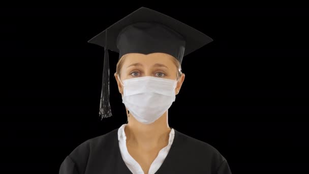 Afgestudeerd studente dame in een medisch masker op zoek naar camera, Alpha Channel — Stockvideo