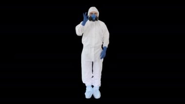Koruyucu giysi giyen doktor, tamam işareti ve baş parmağını Alfa Kanalı 'na gösteriyor.