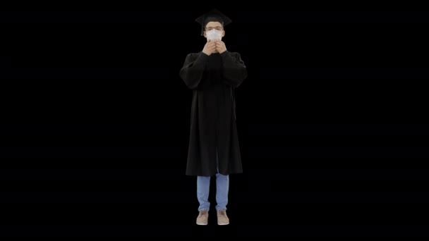 Młody człowiek w sukni dyplomowej w masce medycznej, kanał Alfa — Wideo stockowe