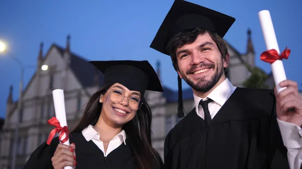 一对快乐的年轻夫妇在毕业典礼上对着镜头微笑. — 图库照片