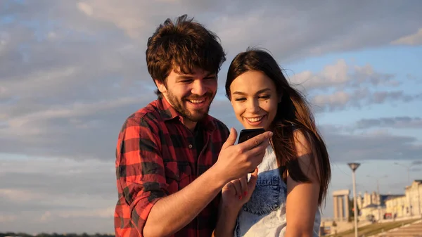 Happy couple watching photos in a smart phone outdoors. — Stock Photo, Image