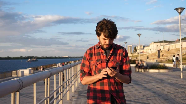 Homme décontracté marchant à l'extérieur lisant un message texte sur son ph intelligent — Photo