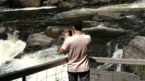 Людина фотографує водоспад на смартфоні. Концепція подорожей — стокове фото