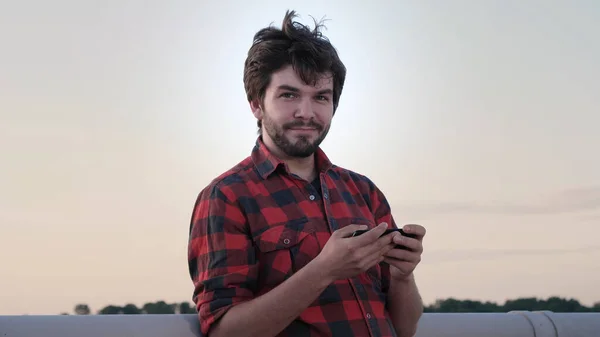 Hombre guapo jugando un juego en el teléfono y sonriendo a la cámara . —  Fotos de Stock