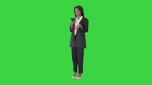 Sourire femme noire textos sur son téléphone portable sur un écran vert, Chroma Key.