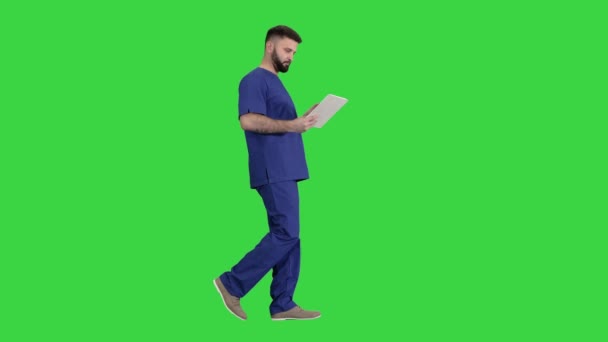 Självsäker koncentrerad fokuserad kirurg med digital tablett på en grön skärm, Chroma Key. — Stockvideo