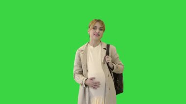 Yeşil ekranda yürüyen mutlu hamile kız öğrenci, Chroma Key.