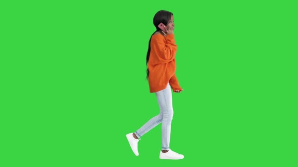 Emocionální africká americká žena v jasném jumperu mluvit do telefonu při chůzi na zelené obrazovce, Chroma Key. — Stock video