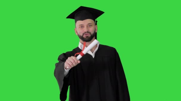 Joyeux jeune homme en chapeau de fin d'études détenant un diplôme et parlant sur un écran vert, Chroma Key. — Video