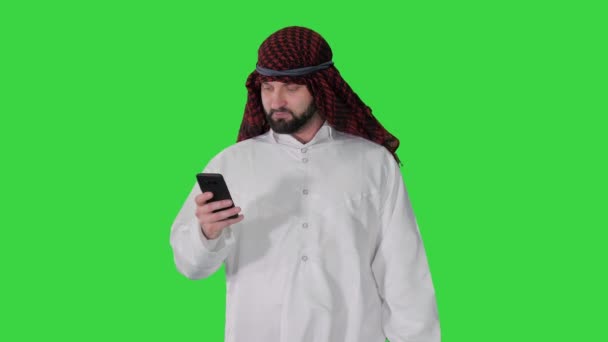 Арабський чоловік використовує смартфон серфінг в Інтернеті або повідомлення під час прогулянки на Green Screen, Chroma Key. — стокове відео