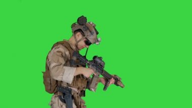 Asker yeşil ekranda yürürken otomatik tüfeğin şarjörünü kurşunla değiştiriyor, Chroma Key.