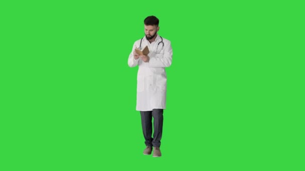 Chodící lékař nebo lékař muž drží pero a notebook hledá nápad na zelené obrazovce, Chroma Key. — Stock video