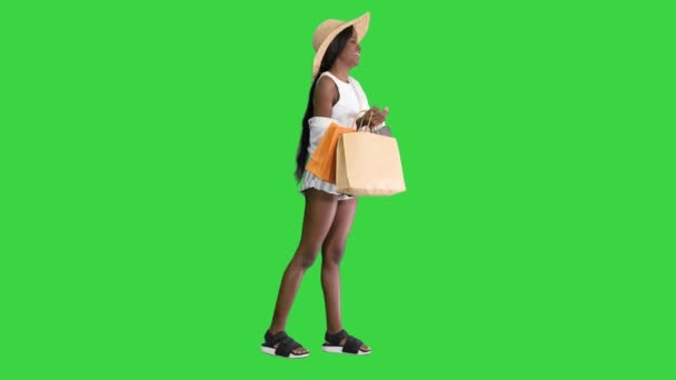 Sorrindo afro-americana em chapéu de palha posando com sacos de compras em uma tela verde, Chroma Key. — Vídeo de Stock