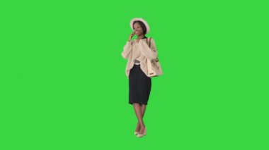Örgü ve şapka giymiş gülümseyen Afro-Amerikan kadın yeşil ekranda, Chroma Key 'de telefonuyla konuşuyor..