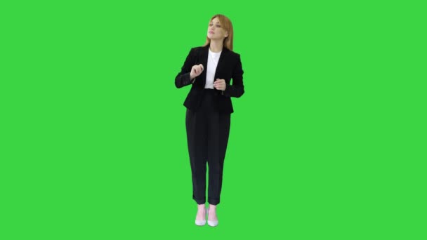 Jeune femme d'affaires présentant quelque chose pointant vers des objets virtuels sur ses côtés sur un écran vert, Chroma Key.