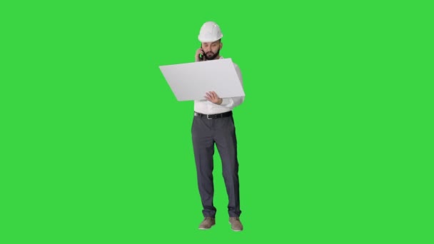 Ingenieur für Formalbekleidung und Hardhat im Gespräch mit dem Kunden oder Auftragnehmer auf dem Mobiltelefon und Blick auf die Blaupause auf einem Green Screen, Chroma Key. — Stockvideo