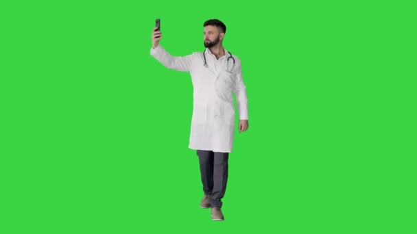 Médico tomando una selfie con teléfono inteligente mientras camina en una pantalla verde, Chroma Key. — Vídeos de Stock