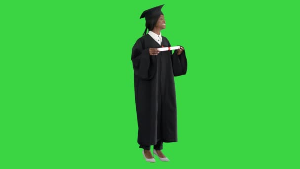 Souriante étudiante afro-américaine en robe de remise des diplômes posant avec un diplôme sur un écran vert, Chroma Key. — Video