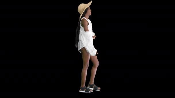 Relajada chica afroamericana caminando con un sombrero de paja y una bolsa, Alpha Channel — Vídeos de Stock