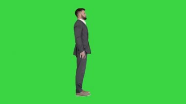 Sakallı, bıyıklı, takım elbiseli, kendine güveni tam bir iş adamı Yeşil Ekran 'ın üzerinde duruyor, Chroma Key.