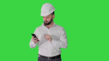 Yeşil Ekranda yürüyen ve akıllı telefon kullanan bir mühendis, Chroma Key.