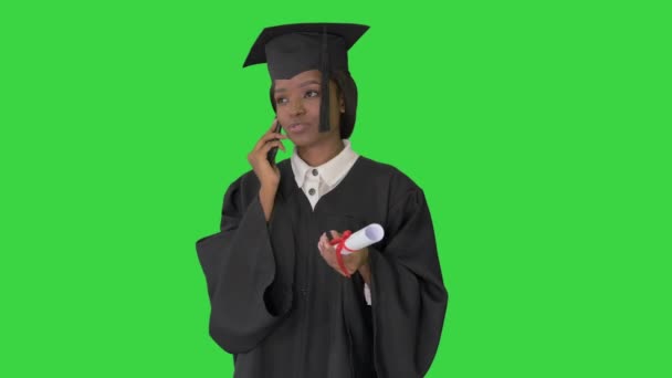 Estudiante afroamericana en bata de graduación hablando por teléfono en una pantalla verde, Chroma Key . — Vídeos de Stock