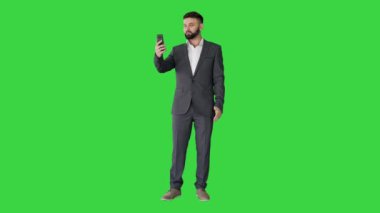 Yakışıklı Türk işadamı akıllı telefonuyla bir video görüşmesi yapıyor. Yeşil ekranda, Chroma Key..