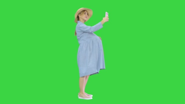 Счастливая беременная женщина в шляпе с помощью смартфона делает селфи на зеленом экране, Chroma Key. — стоковое видео