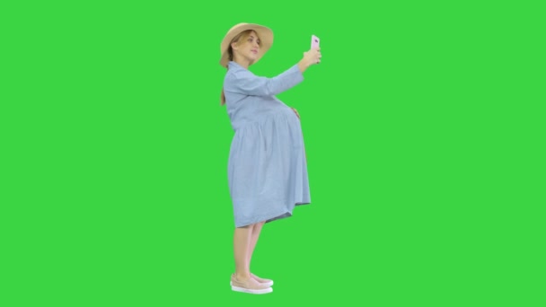 Mulher grávida feliz em um chapéu usando seu smartphone fazendo selfie em uma tela verde, Chroma Key . — Vídeo de Stock