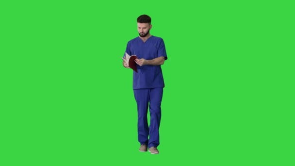 Arzt liest medizinisches Journal, während er auf einem Green Screen läuft, Chroma Key. — Stockvideo