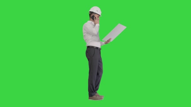 Μηχανικός με επίσημη ένδυση και hardhat μιλώντας με πελάτη ή εργολάβο στο κινητό τηλέφωνο και κοιτάζοντας το σχέδιο σε μια πράσινη οθόνη, Chroma Key. — Αρχείο Βίντεο