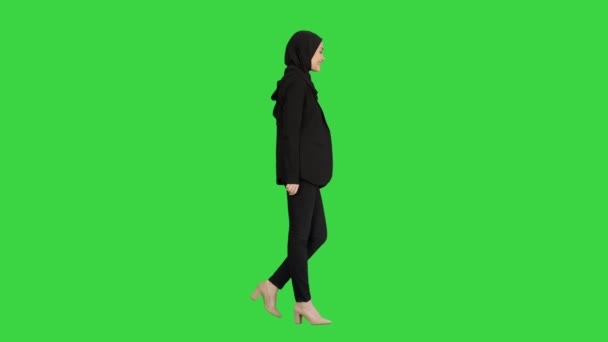 Улыбающаяся исламская женщина-модель в хиджабе идет и смотрит вперед на зеленый экран, Chroma Key. — стоковое видео