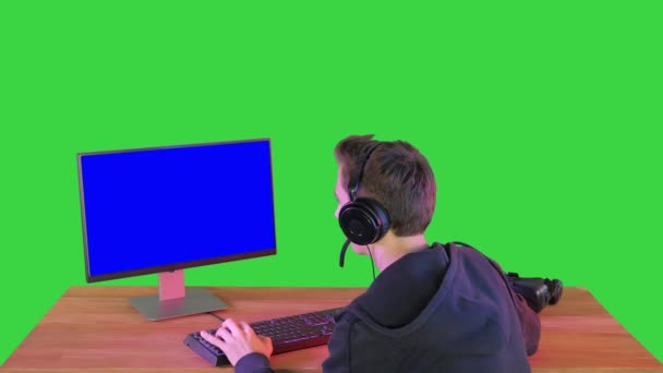 带耳机的兴奋游戏者在绿色屏幕上对着相机微笑，Chroma键. — 图库视频影像