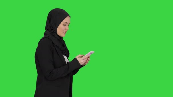 Muselman kvinna messaging på hennes mobiltelefon stund promenader på en Grön Skärm, Chroma Key. — Stockvideo