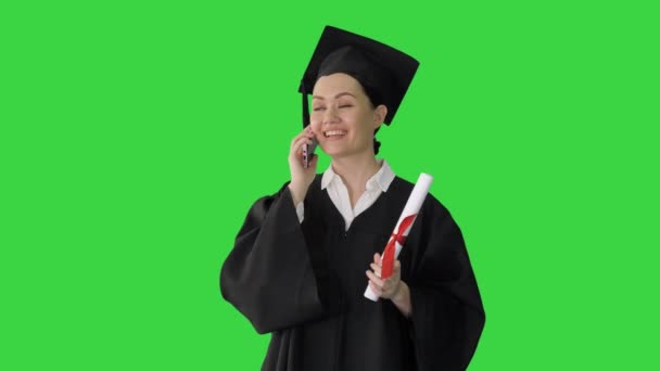 緑の画面上で卒業証書を保持電話で話して卒業ローブの感情的な女性学生,クロマキー. — ストック動画