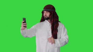 Yeşil Ekran, Chroma Key 'de yürüyen ve telefonuyla selfie çeken Arap bir adam..