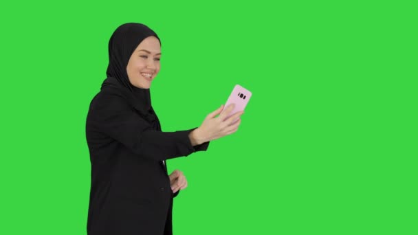 Jovem mulher muçulmana bonita em hijab ter chamada de vídeo em seu telefone como ela anda em uma tela verde, Chroma Key. — Vídeo de Stock