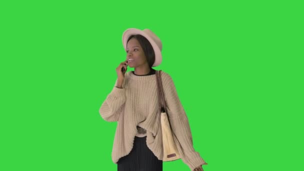 Femme afro-américaine frustrée en pull tricoté et chapeau blanc parlant sur son téléphone sur un écran vert, Chroma Key.