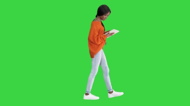 Sorrindo mulher afro-americana usando tablet pc enquanto caminha em uma tela verde, Chroma Key. — Vídeo de Stock