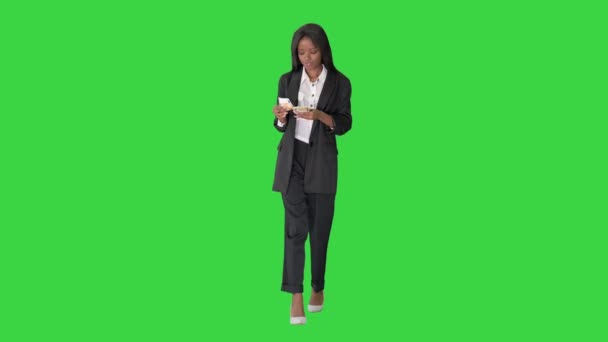 緑の画面、クロマキーを歩いている間にお金を数える幸せなアフリカ系アメリカ人女性. — ストック動画