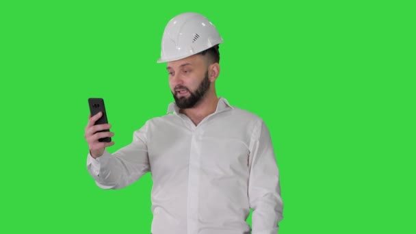 Férfi mérnök visel védő sisak és ing, hogy videohívás a zöld képernyőn, Chroma Key. — Stock videók