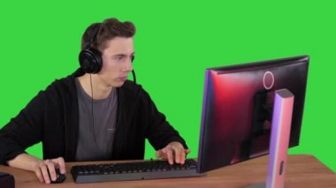 Kulaklıklı oyuncu bilgisayarda video oyunu oynuyor ve yeşil ekranda kazanıyor, Chroma Key.