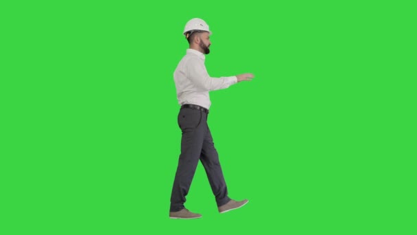 緑の画面で何かを歩くと説明するハードハットのエンジニア,クロマキー. — ストック動画