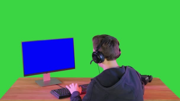 Задній постріл конкуруючого молодого чоловіка, який грає онлайн ігри на комп "ютері на зеленому екрані, Chroma Key. — стокове відео